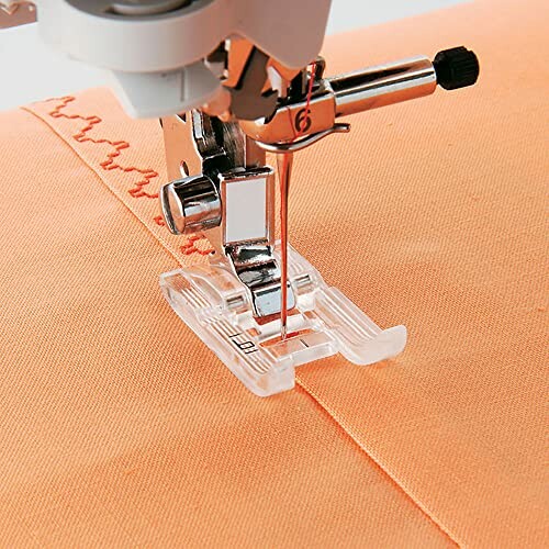 Close-up of a sewing machine needle stitching orange fabric.