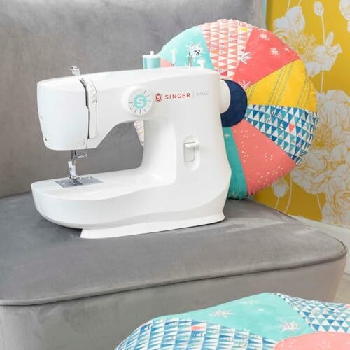 Sewing machine on a couch with colorful pillow.